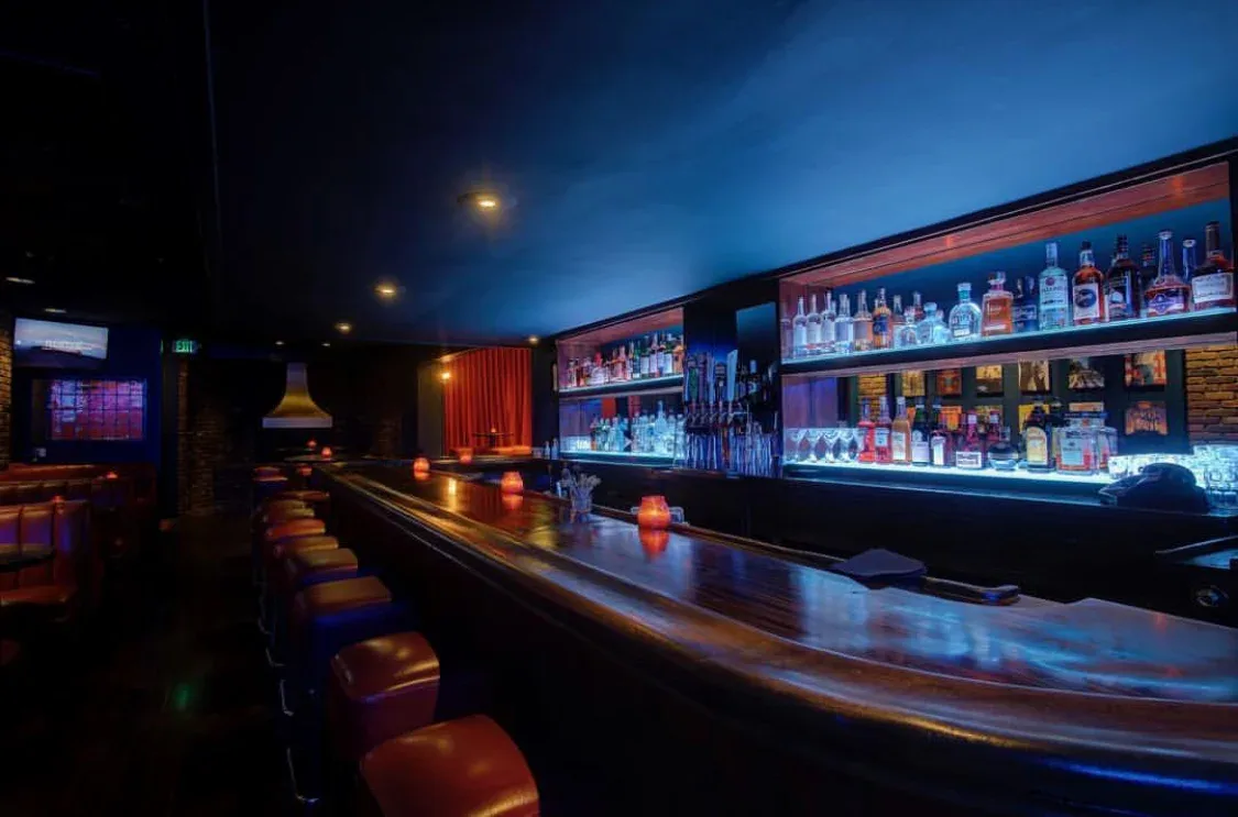 Avignone's neon sign over a red-lit backbar of bottles