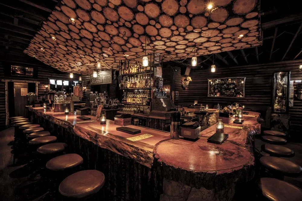 Bigfoot West's log-cabin bar with a mounted bear, bottle shelves, and a pool table