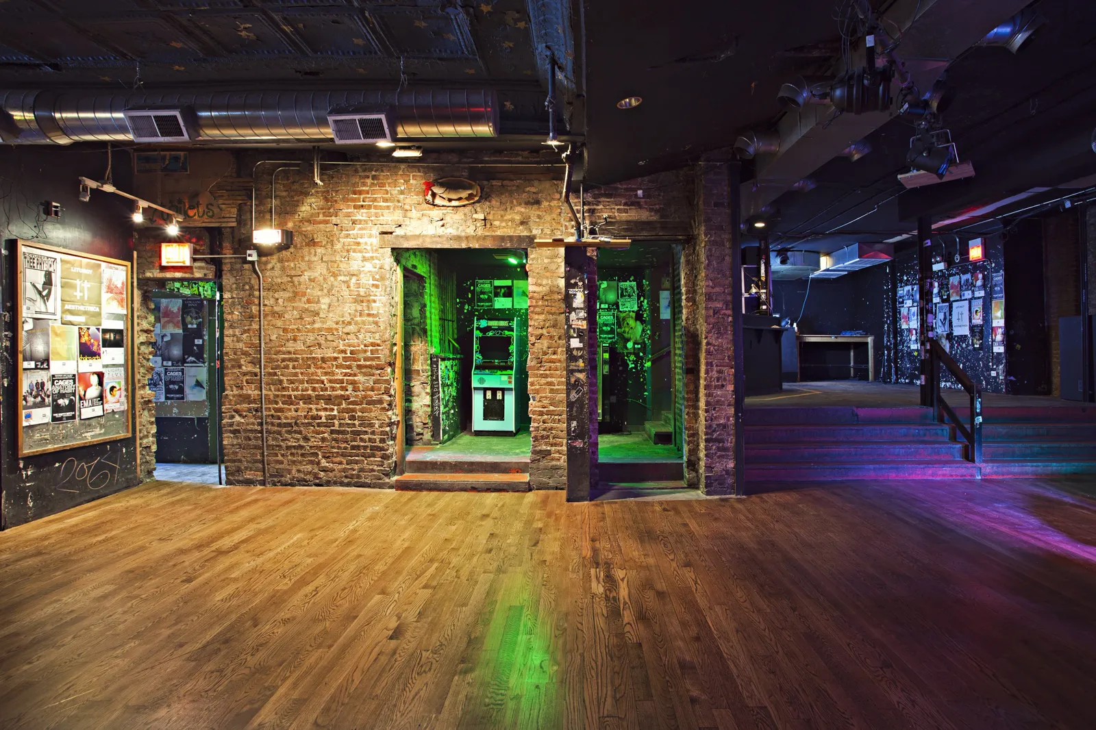 The Empty Bottle back room, with a flyer wall, green-lit arcade nook, and raised stage