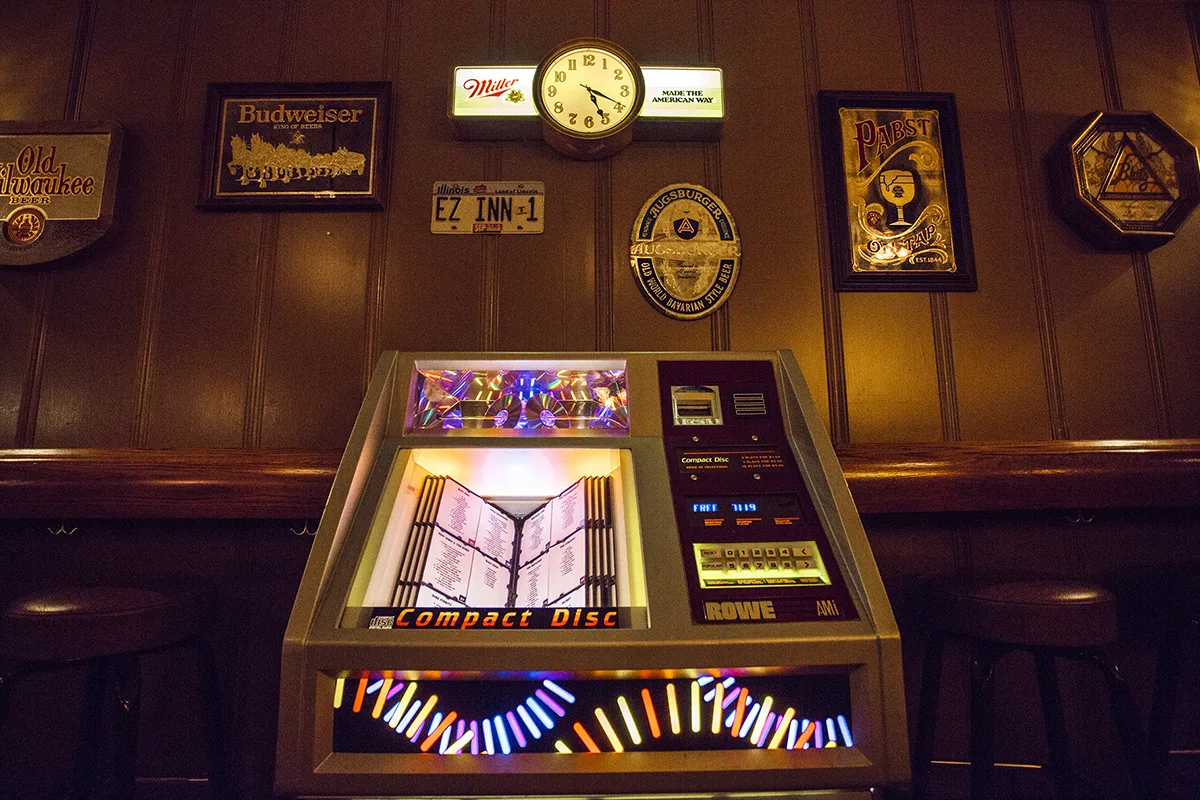 A Rowe AMI CD jukebox under an EZ INN-1 plate and beer signs at EZ Inn