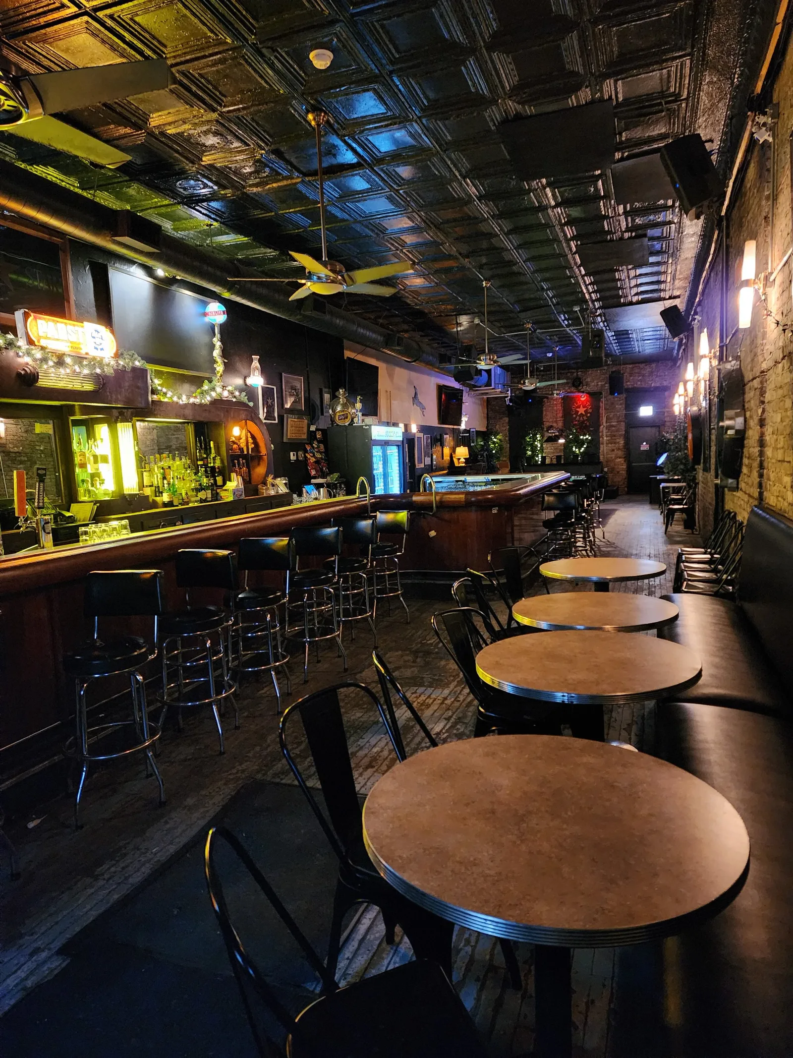 The empty Gold Star Bar room, tin ceiling, brick wall, and black stools along the rail