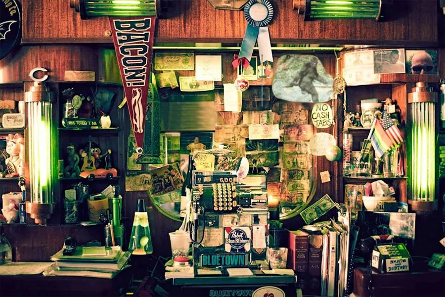 The cluttered Green Eye back bar, vintage register, and green neon