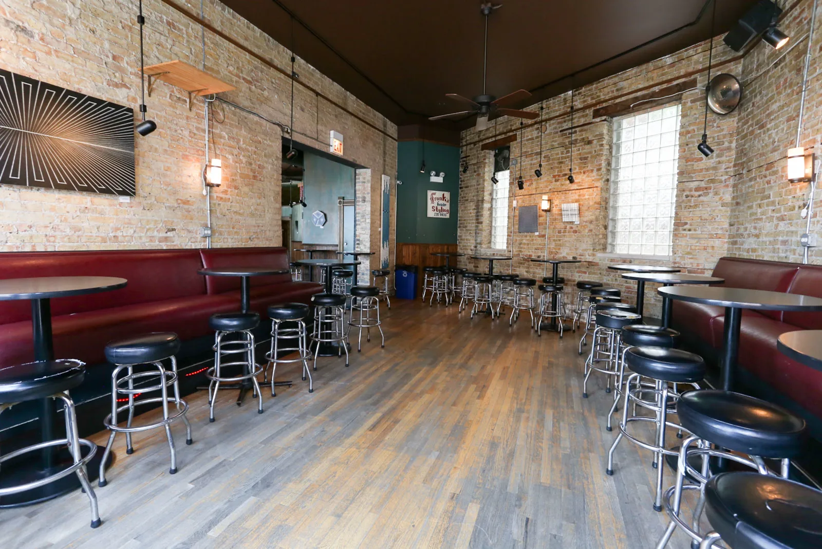 The brick side room at Green Eye Lounge with red booths and black high-tops