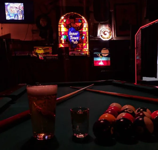 A pool table, crossed cues, and the stained-glass Inner Town Pub heart inside the tavern