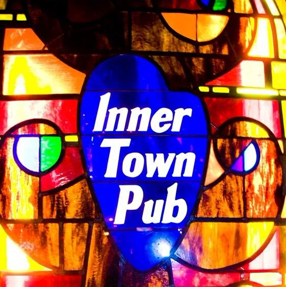 The backlit stained-glass Inner Town Pub logo in red, amber, and blue