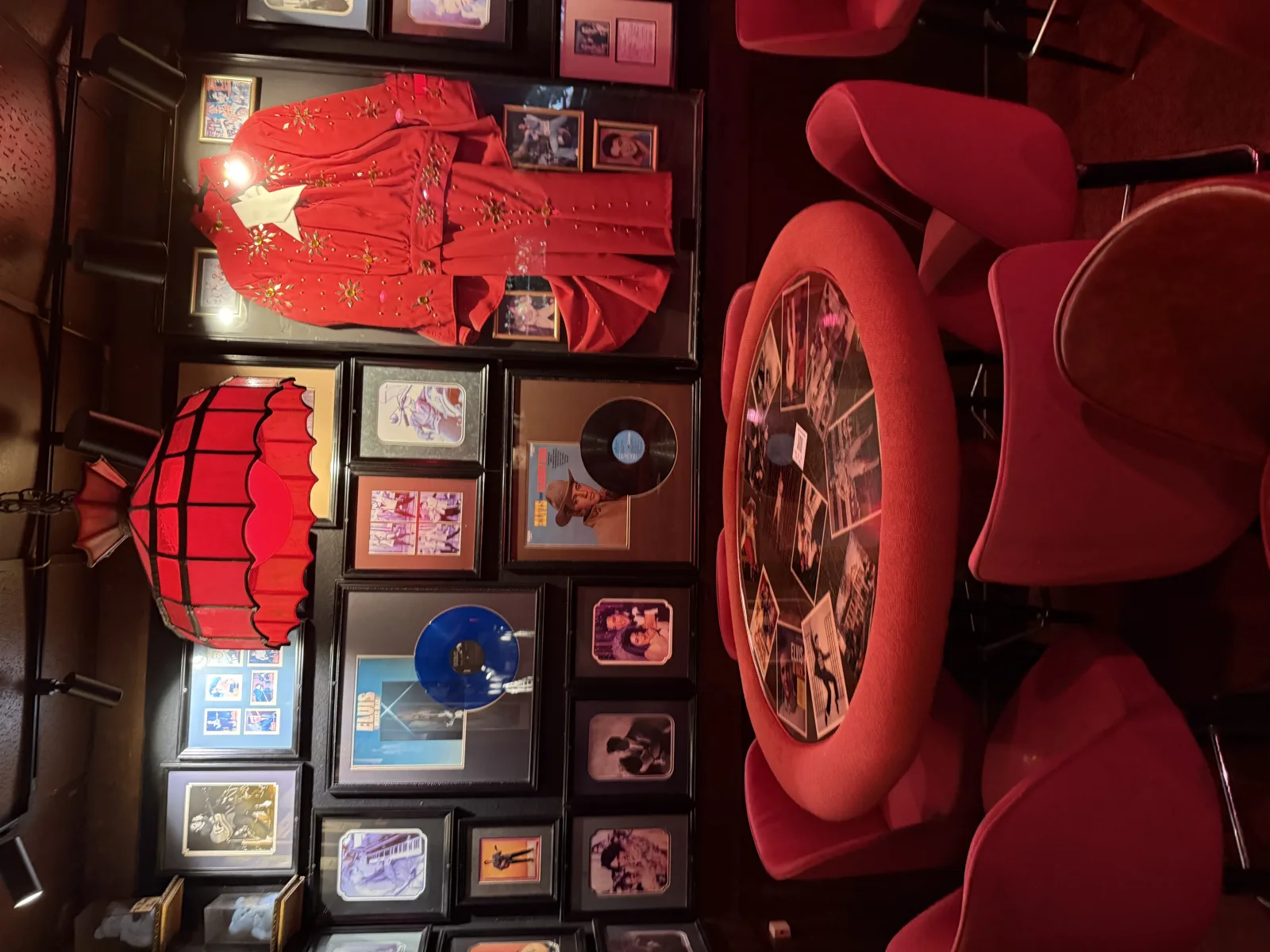 Elvis memorabilia wall and red booth table under a red lamp at Johnny's Hideaway