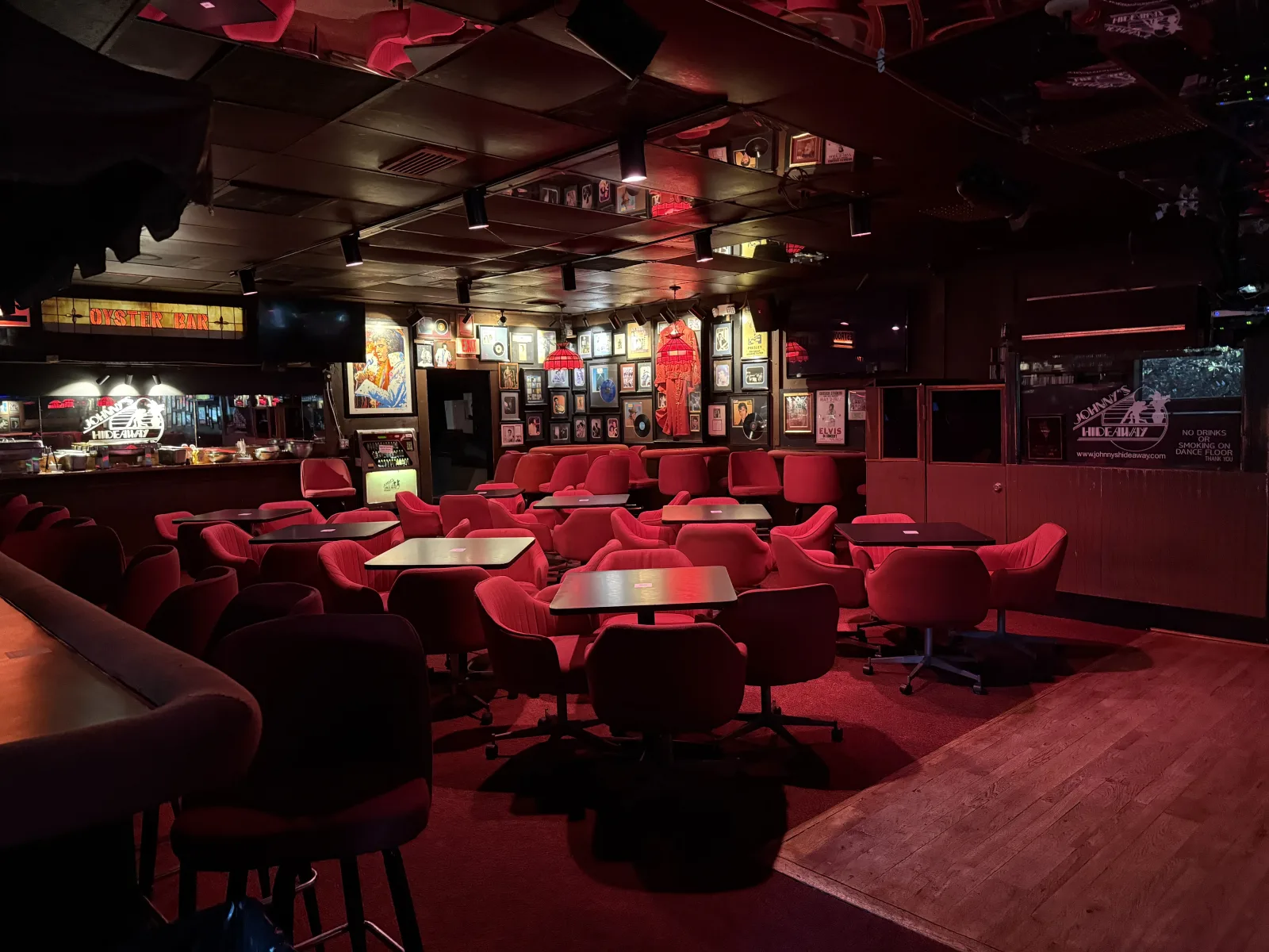 Red swivel chairs, dance floor edge, and Johnny's Hideaway oyster bar signs in the lounge