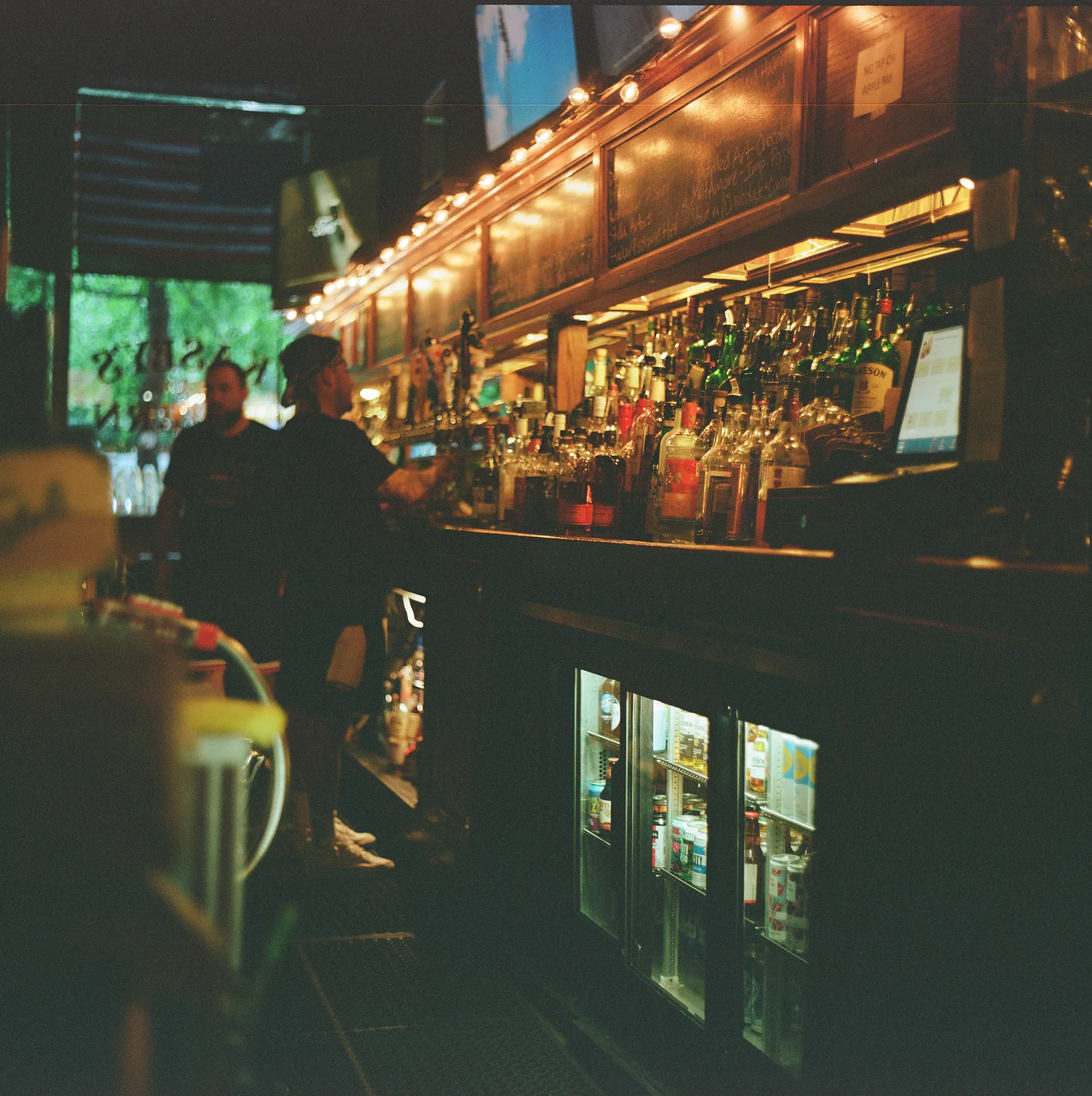 The long wooden rail, liquor shelves, and Kasey's Tavern gold window lettering seen from inside