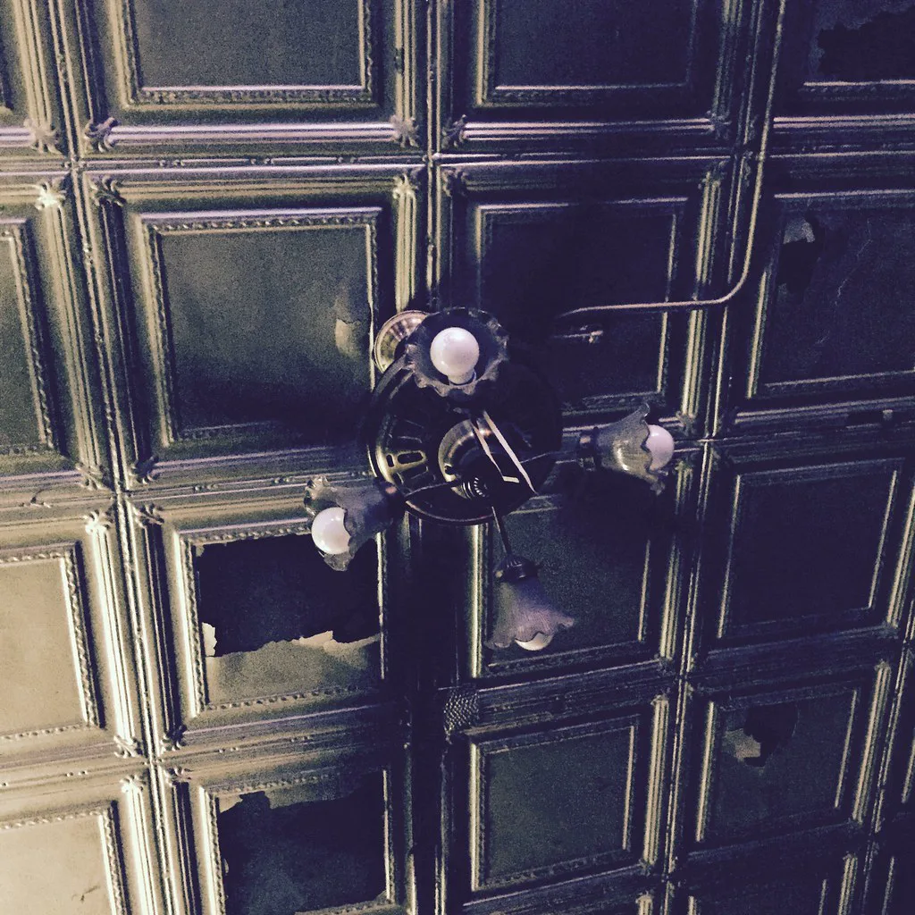 The damaged tin ceiling and hanging light fixture inside L&L Tavern