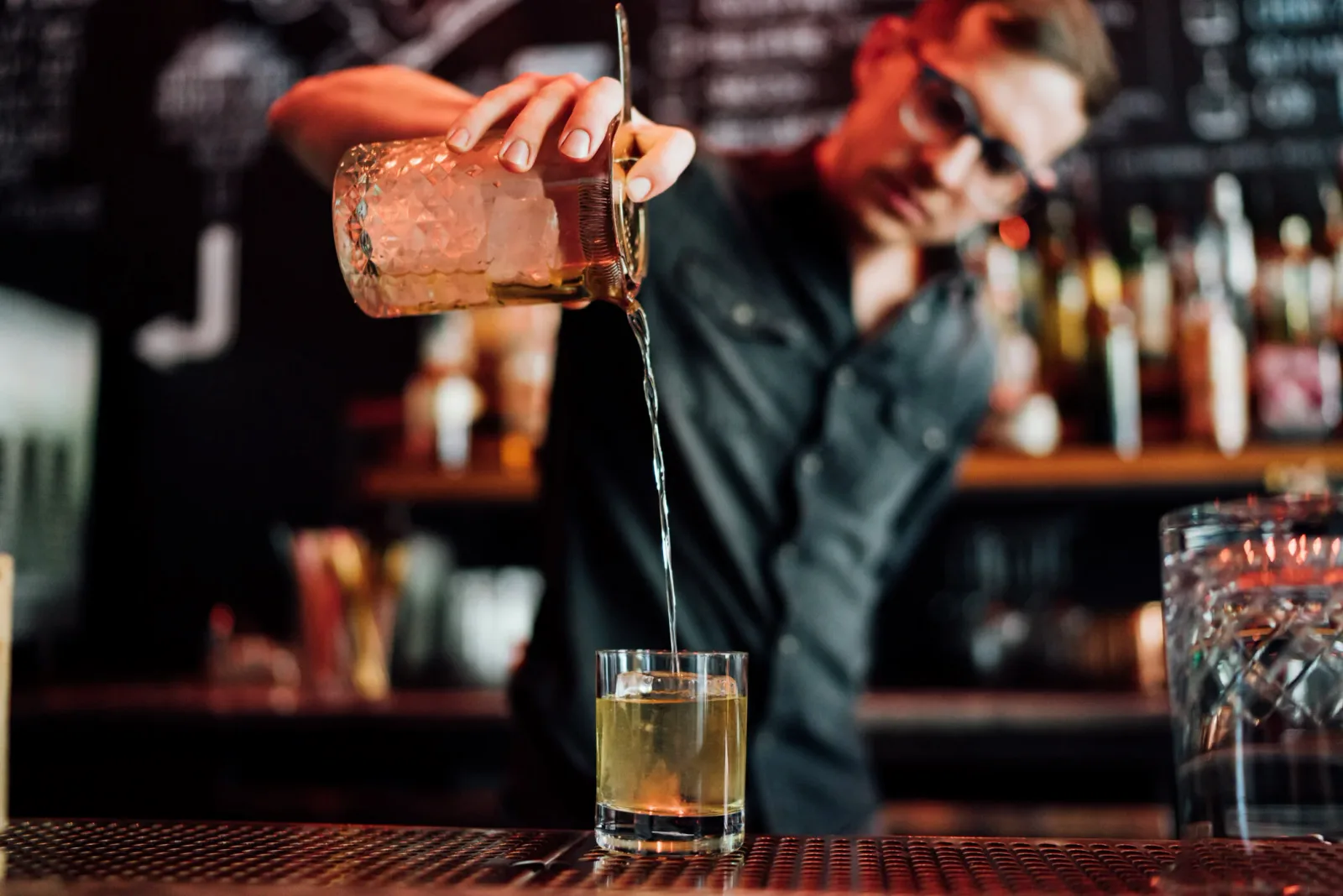Bartender pouring a cocktail from a mixing glass into a rocks glass at Little Spirit