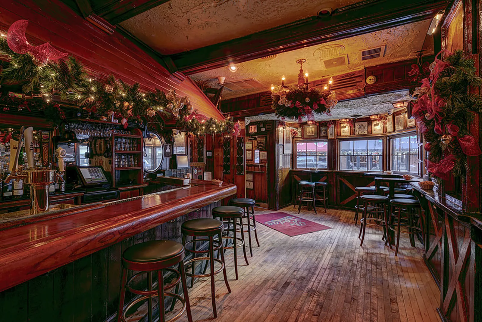 The long wooden bar, Lodge floor mat, and front windows at Lodge Tavern