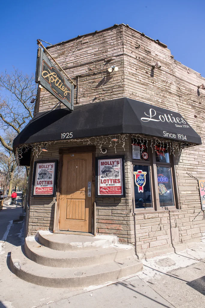 The wooden Lottie's door, hanging Since 1934 sign, and beer neon in the corner window