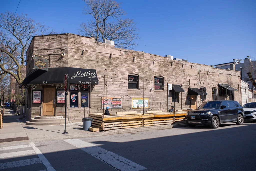 Lottie's Since 1934 awning, hanging wooden sign, and sidewalk patio on a Bucktown corner