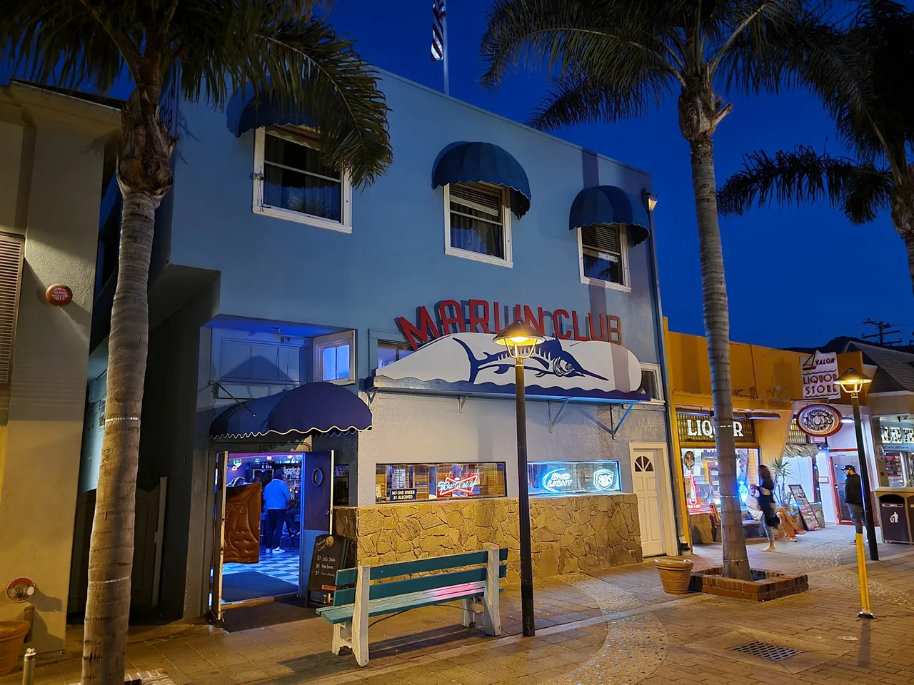 Marlin Club's night storefront with a glowing Marlin Club sign and neon beer signs in the windows