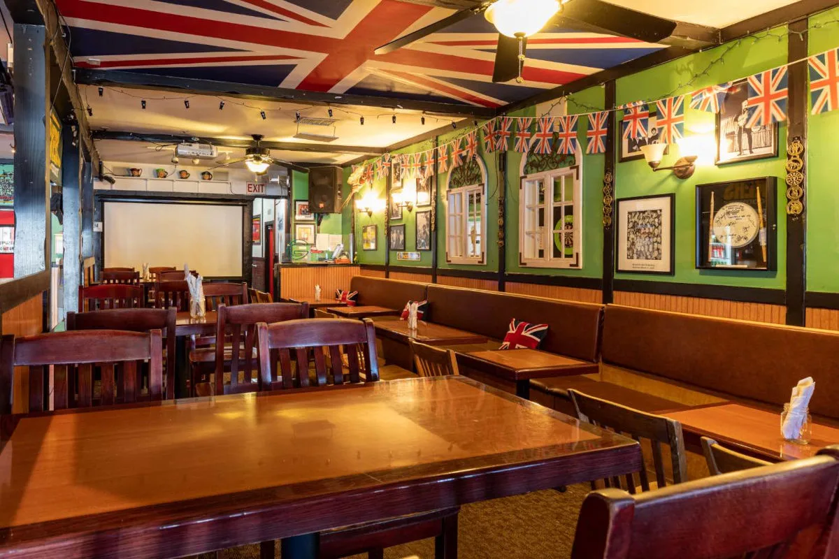 Pickwick Pub's wood bar with red stools, a mirror backbar, and a wall of TVs