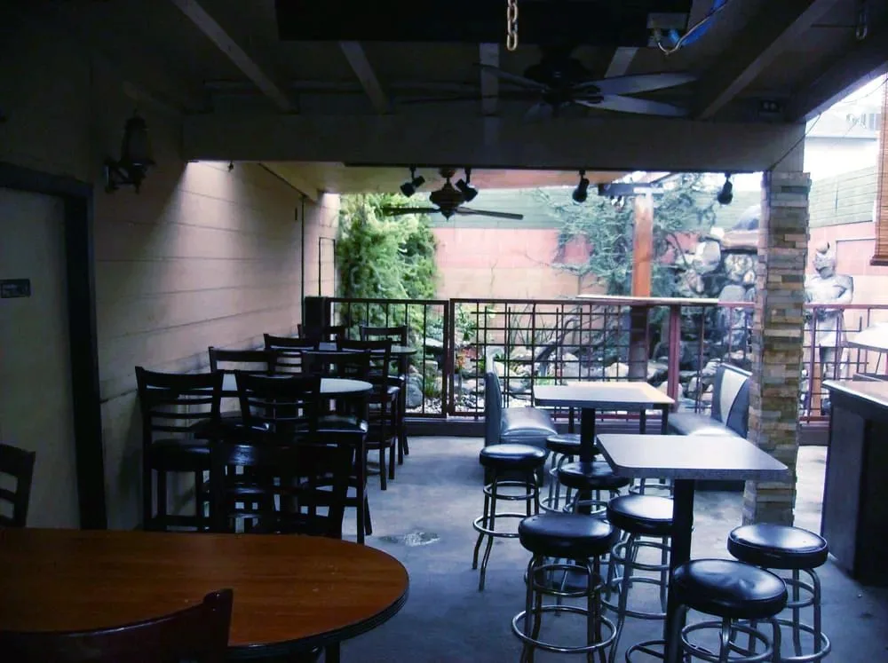 The Crest patio with a rock waterfall, string lights, and umbrella tables