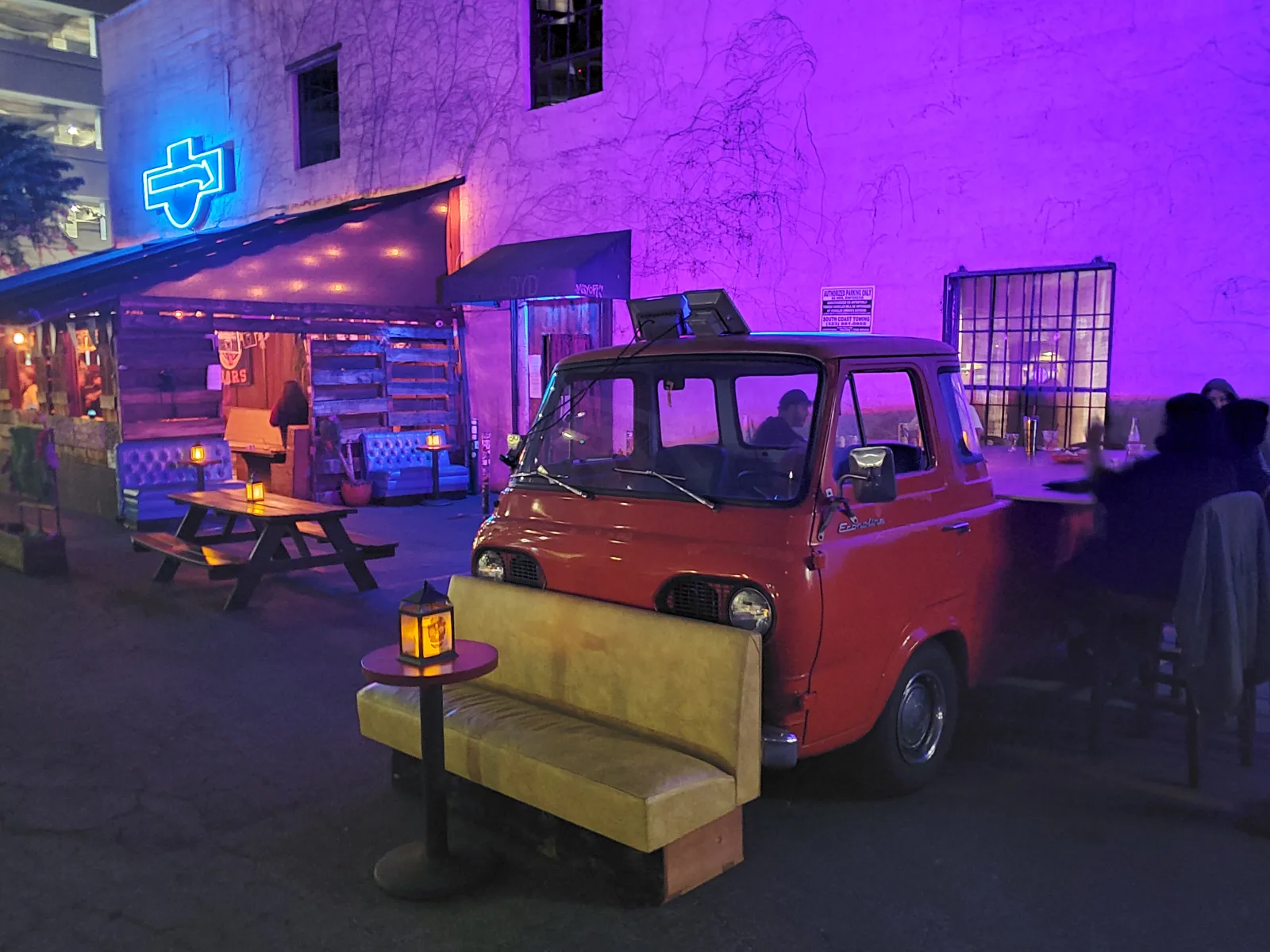 The Escondite patio at night with purple walls and a blue neon sign