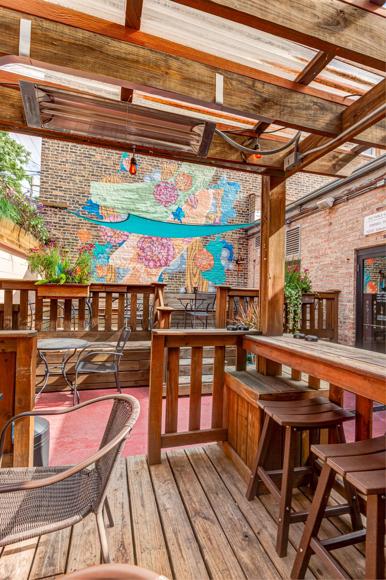 The wooden backyard patio, mural, and high-top rail behind The Long Room