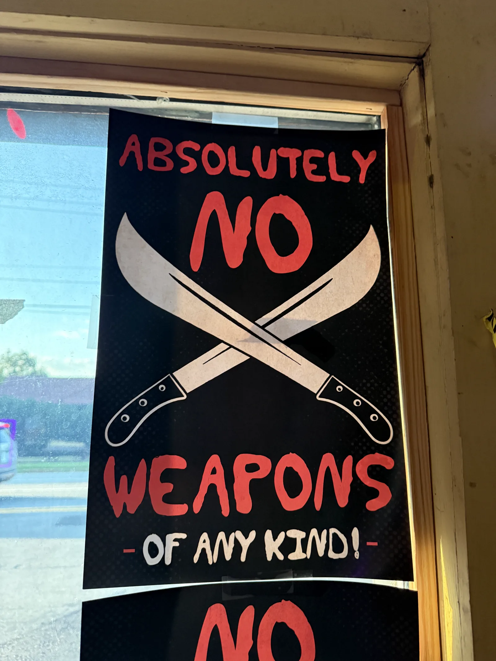 Absolutely No Weapons of Any Kind sign with crossed machetes on the Trackside Tavern door