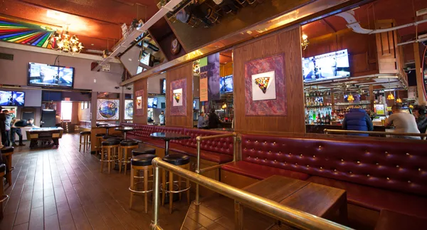 Trunks neon sign above the bar, with a pool table, barstools, and a wall of TVs