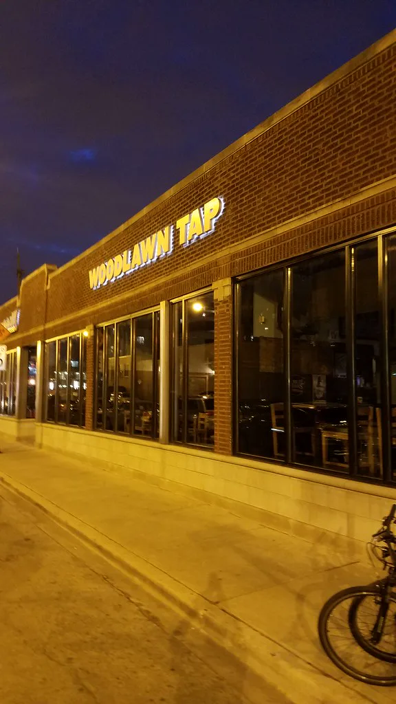 The lighted Woodlawn Tap storefront on 55th Street at night